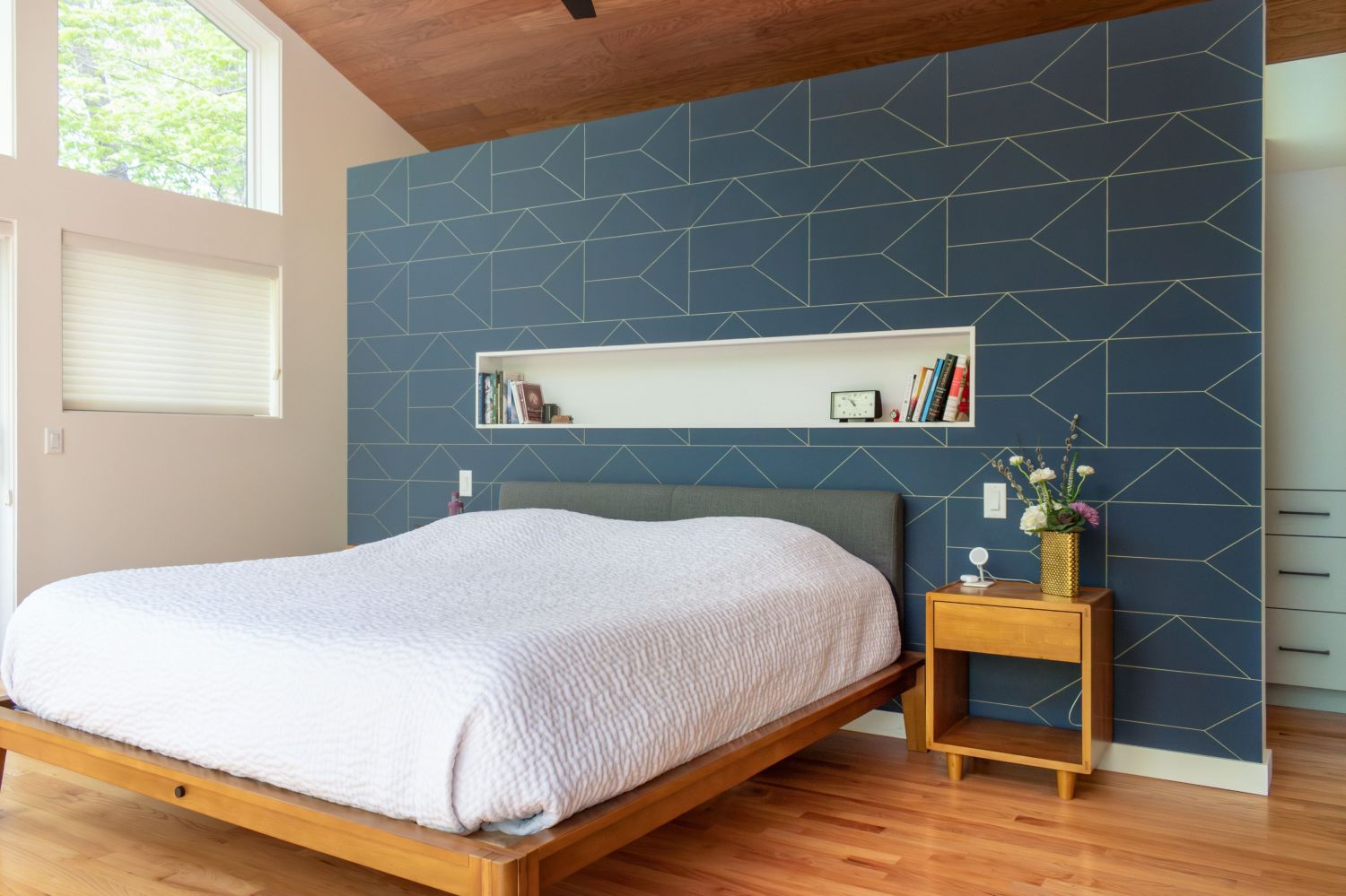 Primary bedroom headwall with geometric wallpaper backlit wall niche