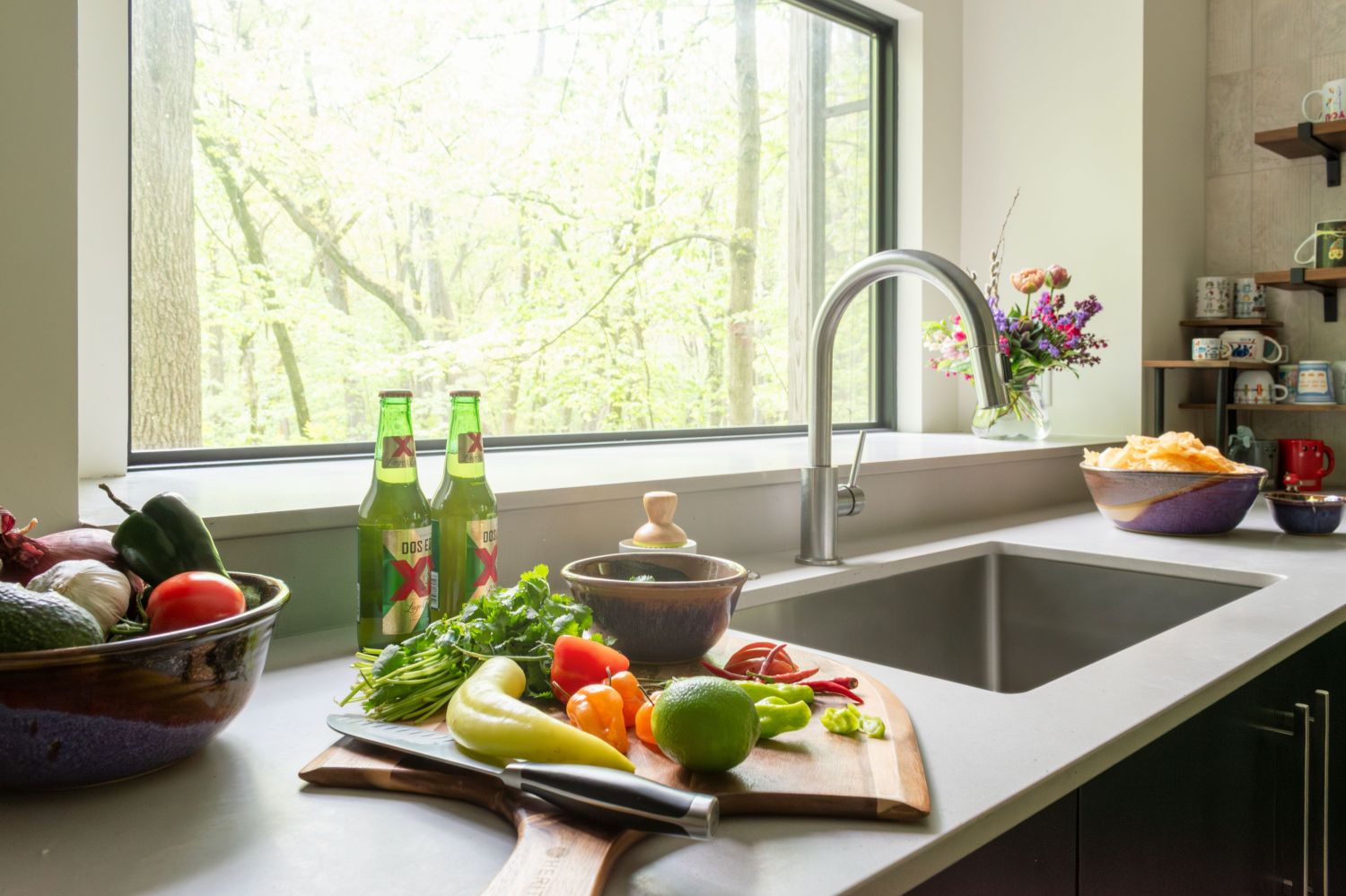 Kitchen sink in front of large picture window in woods