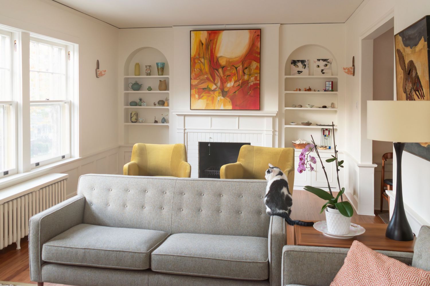 living room with fireplace and built in hutches in historic coop apartment with mid century furniture
