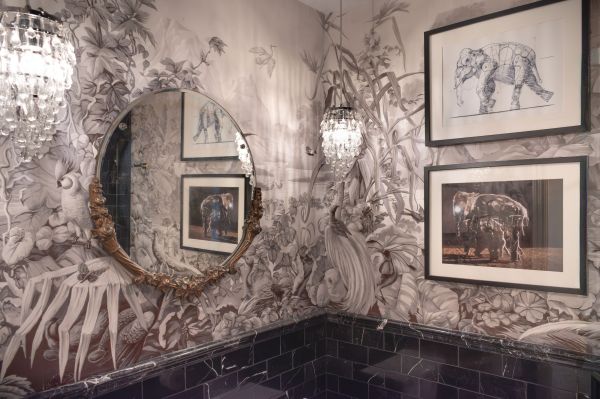 African mural panels in bathroom with round mirror and black marble tile