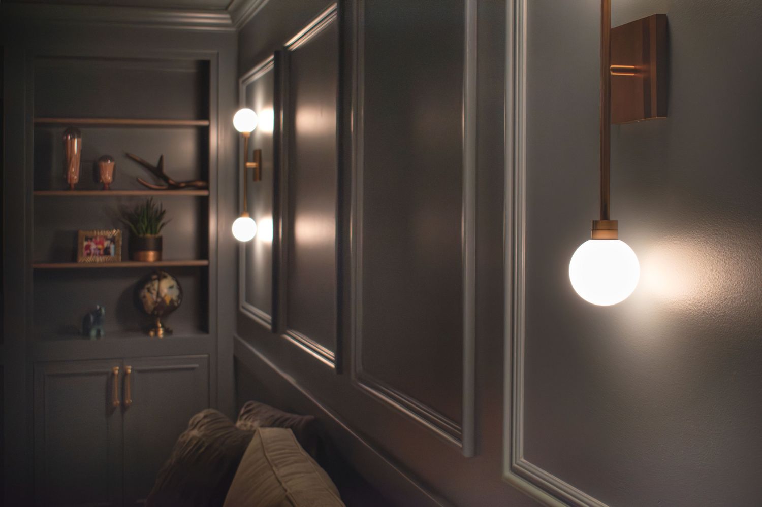 Mara wall sconces in basement with applied molding and a bookcase