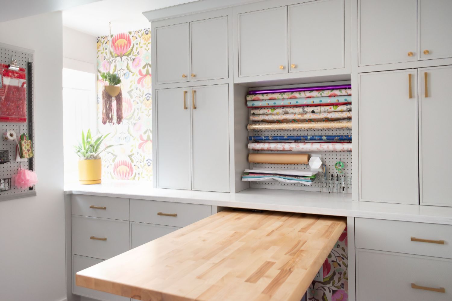 craft station in laundry room with painted gray cabinetry and maple work table