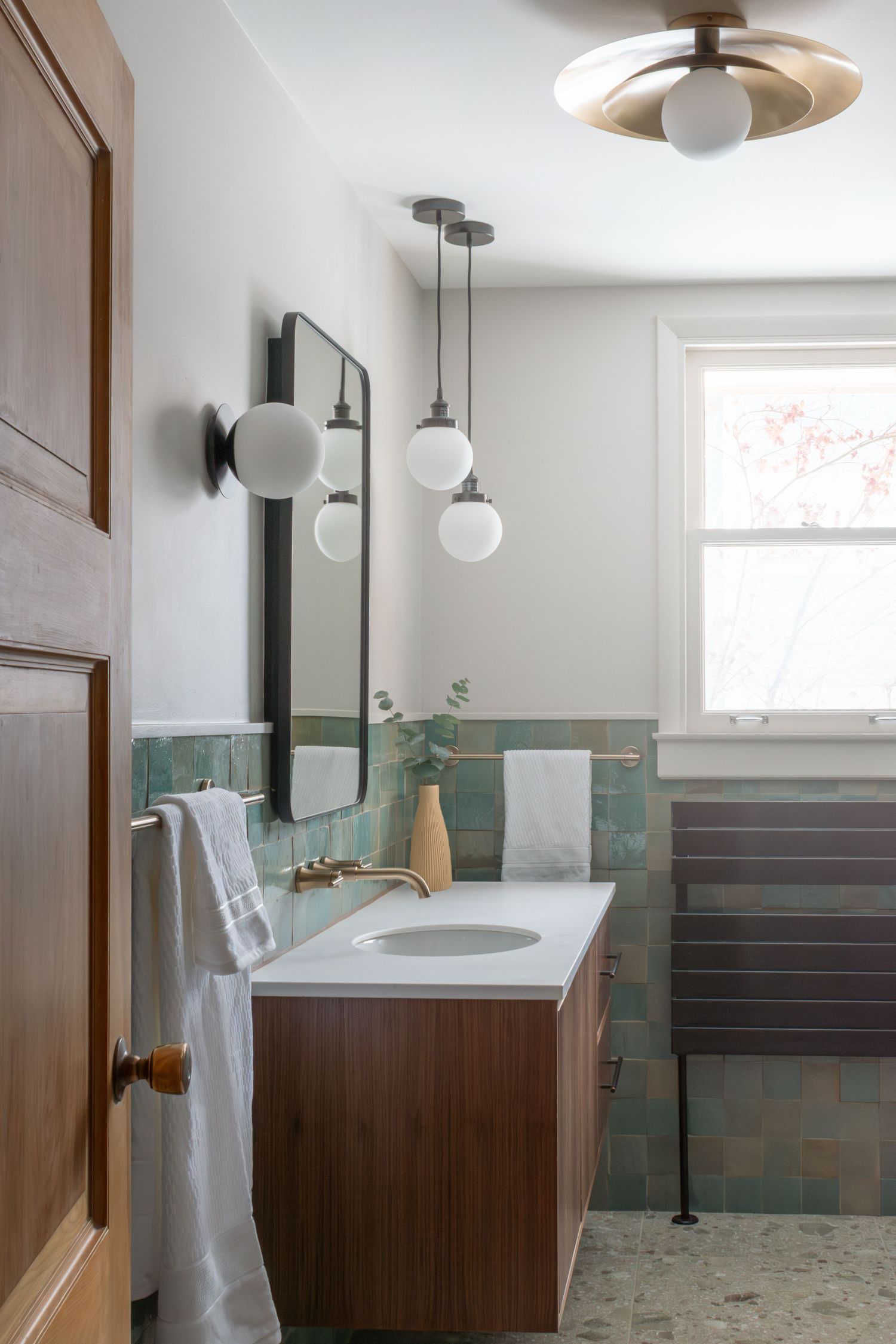 floating walnut vanity and hydronic towel warmer in hall bath